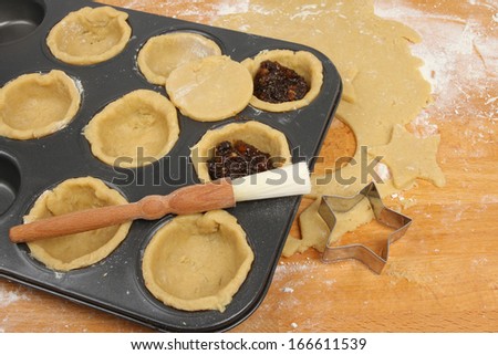 Preparing mince pies, rolled sweet pastry and mince pie ingredients in a baking tray on a wooden worktop