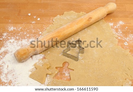 Christmas angel pastry cutter on rolled sweet pastry with a rolling pin on a wooden worktop