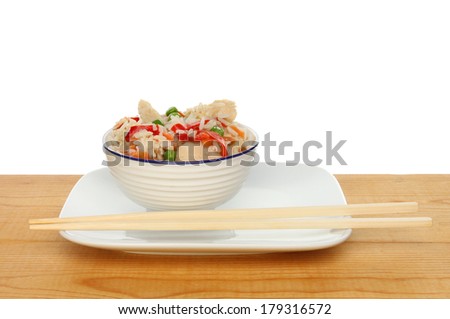 Chinese meal of chicken and vegetable rice in a bowl with chopsticks on a wooden table against a white background