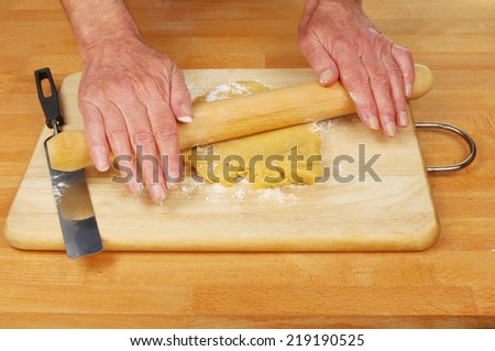 Hands rolling sweet pastry on a board and worktop
