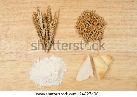 Wheat ears, wheat grains, flour and bread on a wooden board