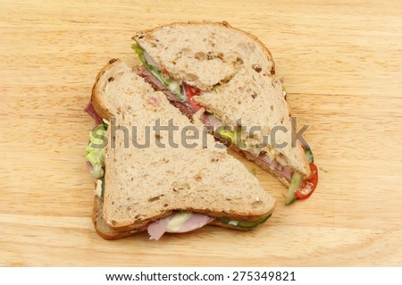 Wholegrain bread ham salad sandwich on a wooden board