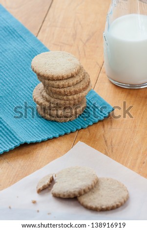 Cookies and milk: stack of butter cookies and a jug with milk on a wooden table
