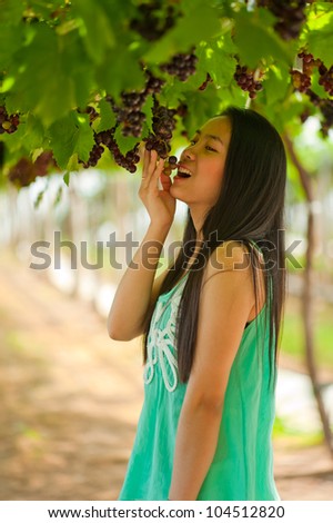 Beautiful Asia Woman testing grapes in vineyard