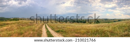 Countryside landscape panorama with cottages on the hills and stormy clouds