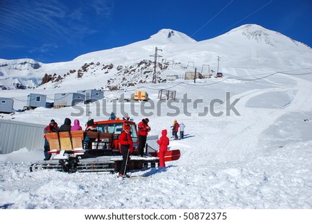 skiers and snowboarders sit down to the grader to go up the mountain.