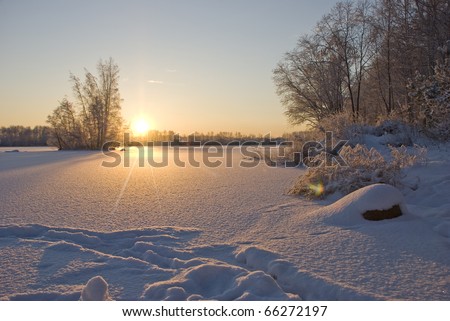 Sunset over  winter  lake  covered by snow