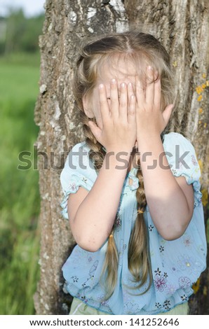 Little girl is playing hide-and-seek hiding face