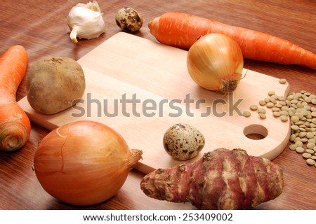 Cutting board with different vegetables on wooden background.