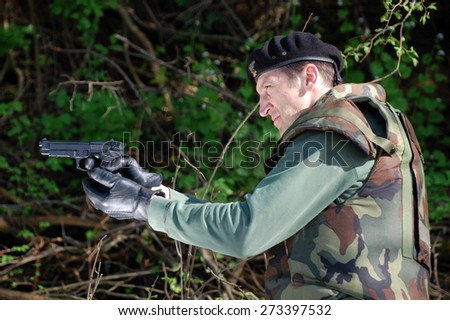The soldier shoots with gun in the forest.