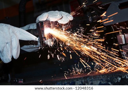 Welder using a plasma cutting machine, wearing protection leather gloves. Sparks flying, plasma machine cutting