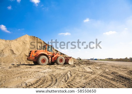 Orange excavator on a construction site working on a pile of gravel. General construction scene
