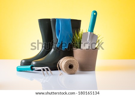 Garden equipment (boots, shovel, rake, pot) over yellow background