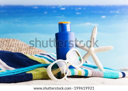 Collection of beach items - lotion, starfish, beautiful towel, sunglasses