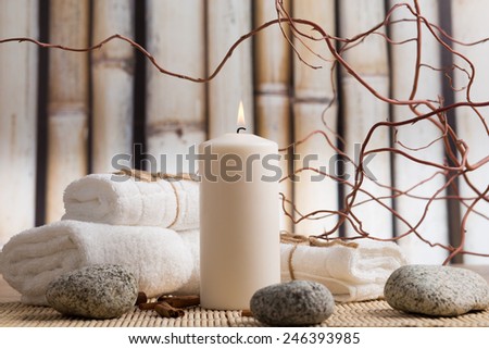 Wellness concept with white candle, white towels and grey stones