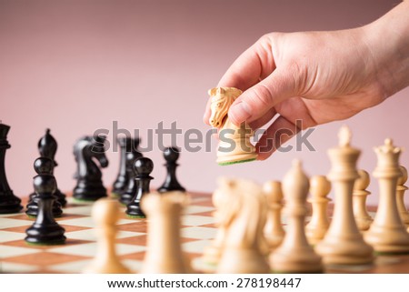 Conceptual image depicting making a strategic move with a hand moving a chess piece on a chessboard during a game