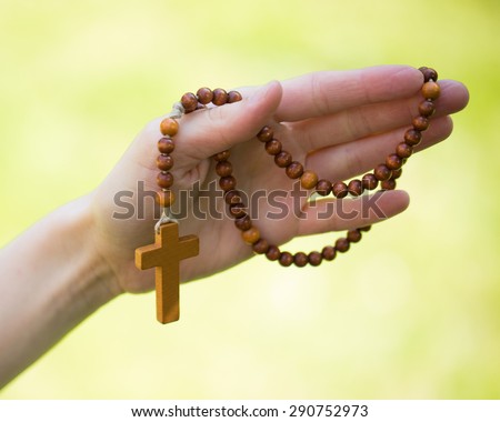 Christian prayer beads and crucifix in the hand of woman