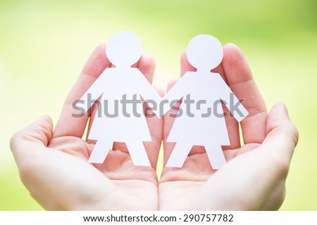 unity concept - close up of hands holding paper gay couple people cutout over green background