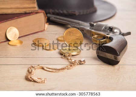 Gambling items - revolver, golden coins, golden watch on wooden background