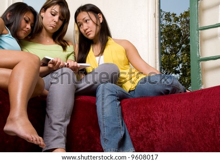 3 females reading a book that is making them express sad emotions.
