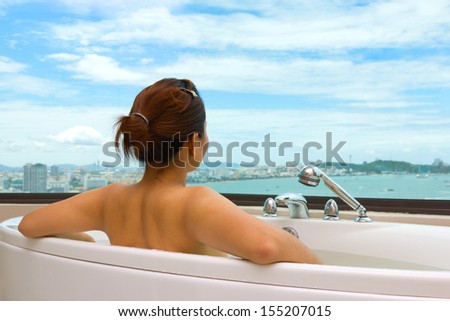 Woman in bathtub looking sea view