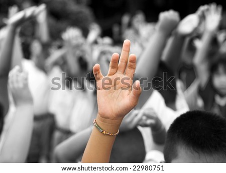 hand in color raised among others hands in black and white background