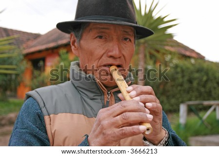 Ecuador man making music with a flute he is trying to sell.