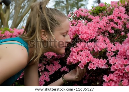 A female leaning over to smell the azaleas.