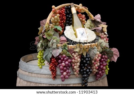 A basket of grapes with a bucket of ice and a bottle of wine sitting on top of a barrel.