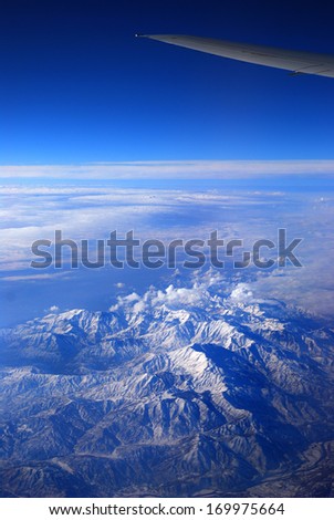 wing transport aircraft over snow-covered mountains under blue sky