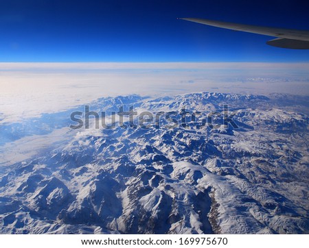 wing transport aircraft over snow-covered mountains under blue sky