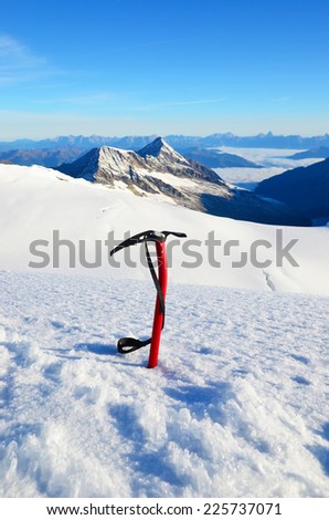 Ice ax stuck in the snow high in the mountains above the glacier
