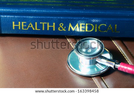 Stethoscope and medical text book on the doctor\'s desk.