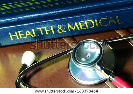 Stethoscope and medical text book on the doctor\'s desk.