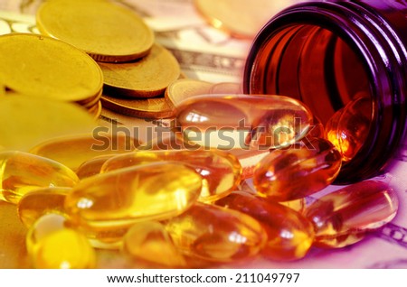 Soft gelatin dietary supplement oil capsule and money in drug expense concept.