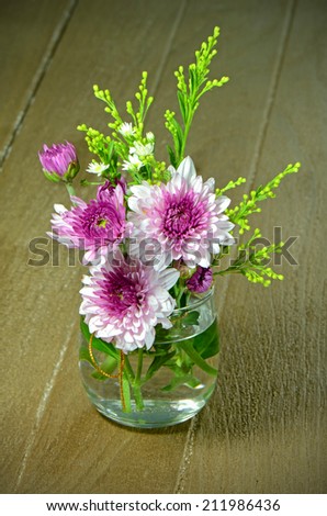 Small Bouquet of Spray Type of Purple Chrysanthemum (Dendranthemum grandifflora) in a Glass on Old Wood Background.