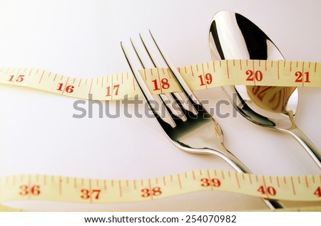 Tape Measure, Fork and Spoon in Waistline and Weight Control Concept by Diet Control.