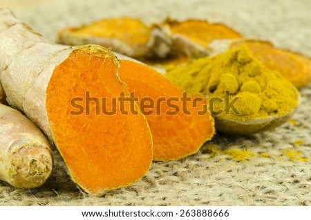 Turmeric Root and Powder on Gunny Background.