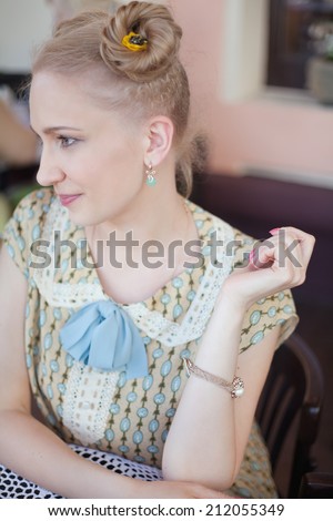 Portrait of beautiful blonde girl in romantic retro dress at table in outdoor cafe