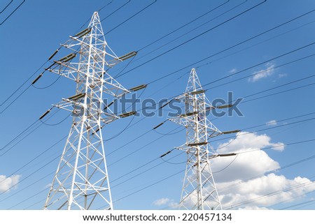 Power transmission high voltage lines on the white supports against blue sky