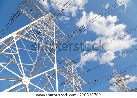 Power transmission high voltage lines on the white supports against blue sky