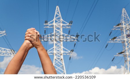 Hands crossed in assent against the background of power transmission lines and blue sky