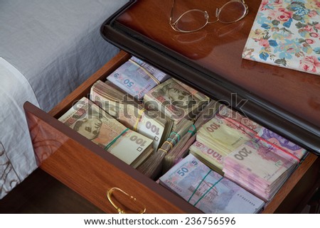 Bundles of banknotes in bedside table filled with Ukrainian cash