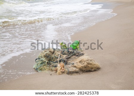 Tangled remains of fishing nets thrown wave on the sea shore