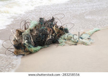 Tangled remains of fishing nets thrown wave on the sea shore