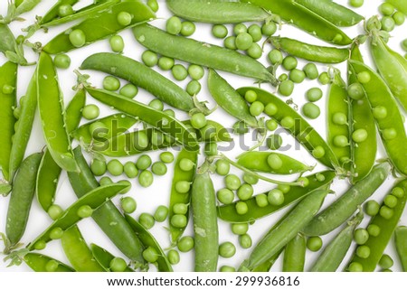 Peas uniformly laid out on a white background. Pods of green peas and pea spreaded as a texture.