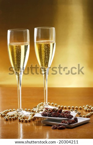 Glasses of champagne with gold background with dried raisins - new year\'s eve
