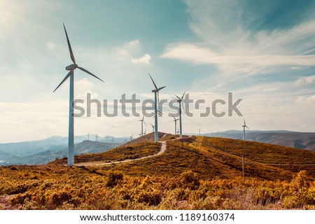 Wind turbines on beautiful sunny summer autumn mountain landsape. Curvy road through mountain Eolic park. Green ecological power energy generation. Wind farm eco field