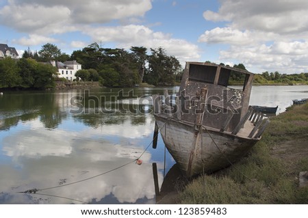 ruins of an old broken boat on the shore of a river