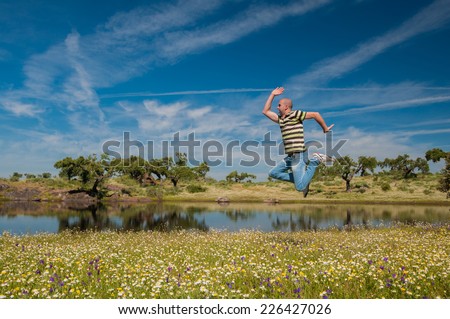 Man jumping in the pastures and pond in Extremadura, Spain. Many oak trees and blue sky